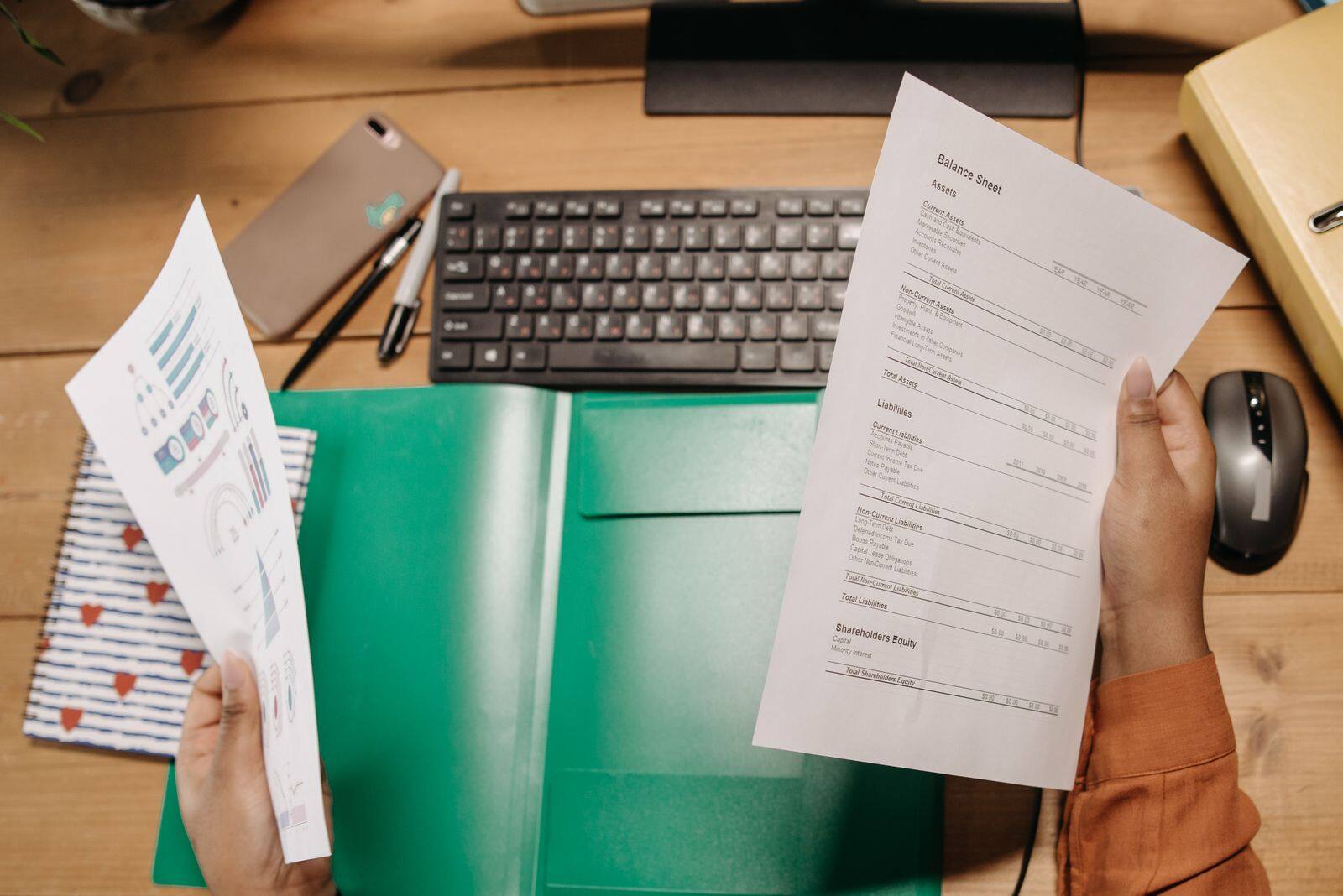 Manos revisando registros y documentos sobre un escritorio